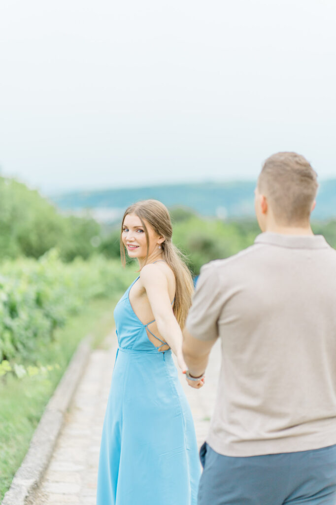Paarfotos und Hochzeitsfotos in den Weinbergen Süßes Paar in Türkise Kleid und Chino vor einem großen Baum und einem charmanten Steinweg