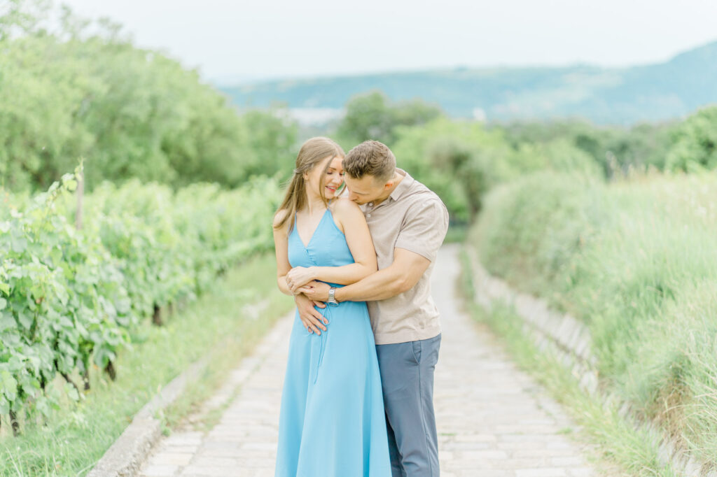 Paarfotos und Hochzeitsfotos in den Weinbergen Süßes Paar in Türkise Kleid und Chino vor einem großen Baum und einem charmanten Steinweg