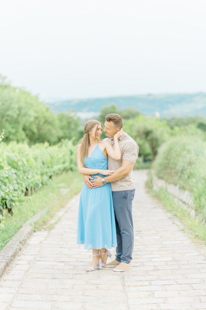Paarfotos und Hochzeitsfotos in den Weinbergen Süßes Paar in Türkise Kleid und Chino vor einem großen Baum und einem charmanten Steinweg
